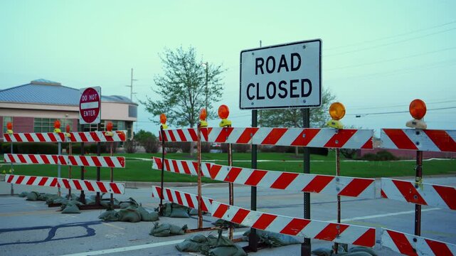 Blocked roadway with barricades and warning sign ROAD CLOSED and STOP at dusk showing restricted access and construction area.
