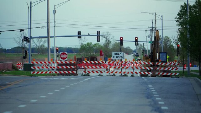 Blocked roadway with barricades and warning sign ROAD CLOSED at dusk showing restricted access and construction area. Wide view