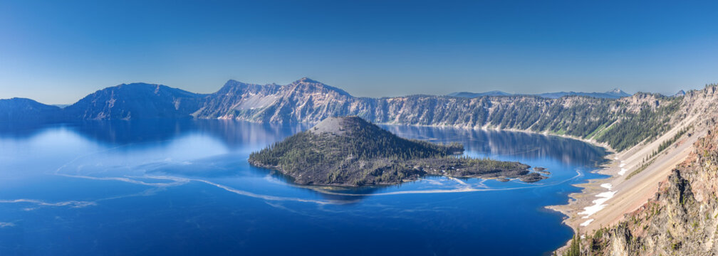 Deep blue Crater Lake surrounded by steep volcanic caldera cliffs with Wizard Island under a clear Oregon sky