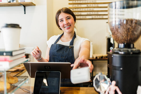 Barista presenting contactless payment reader for customer transaction