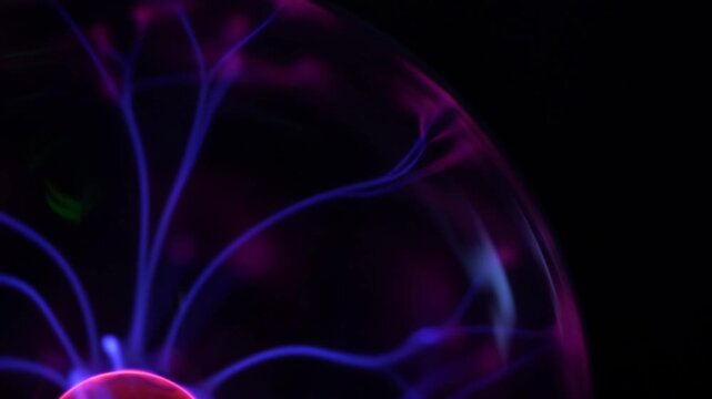 Detailed view of multiple blue and violet plasma arcs radiating symmetrically from a central pink electrode within a glass sphere showing gas ionization.