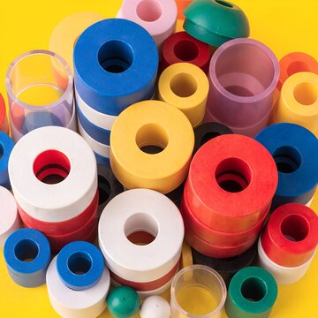 Colorful Plastic Bottle Caps and Containers Arrangement on Yellow Background.