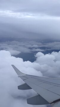 Airplane wing above storm clouds during flight turbulence. Airplane wing shaking slightly during turbulent flight above dramatic clouds. Air travel and aviation weather concept.