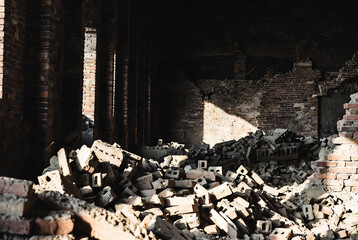 Obraz premium Abandoned brick ruins, likely a demolished building or structure, with sunlight illuminating the rubble.