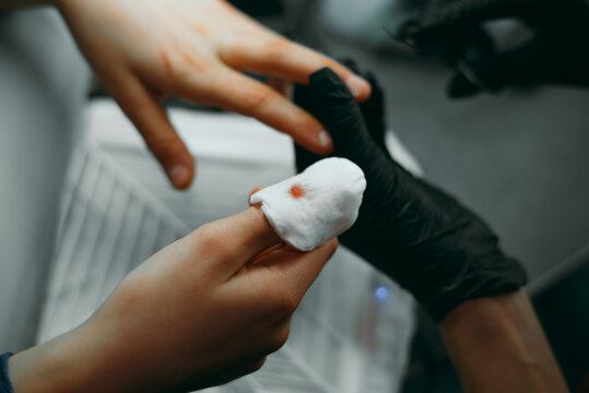 A person is applying a bandage to a finger injury with clear focus on hands and medical supplies. The action suggests a situation requiring first aid, highlighting care and attention to health