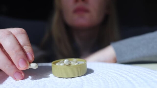 Woman taking iron supplement capsule with glass of water. Female health care, iron deficiency anemia treatment, vitamins and minerals intake for wellness.