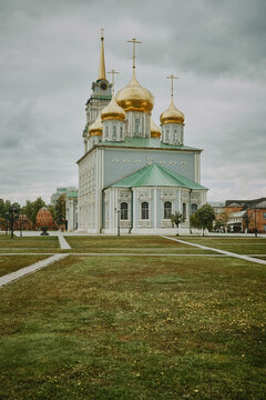An orthodox church standing on a green field with dandelions