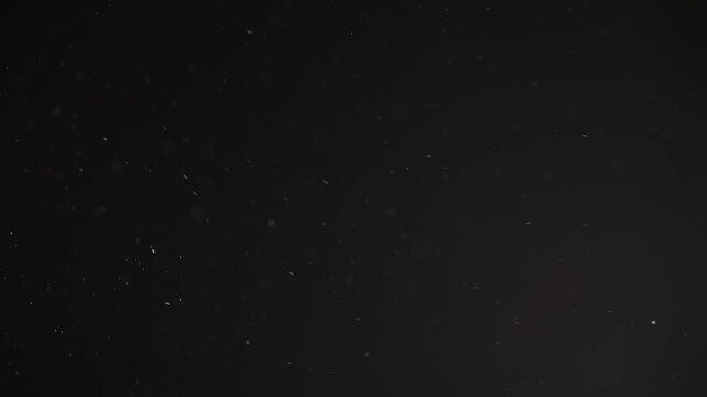 Real dust particles floating mid air over dark background