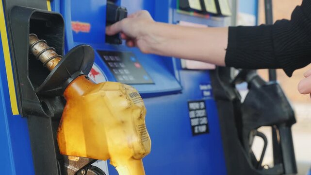 Woman paying for gasoline at gas station pump with credit card on touch screen display, fueling vehicle with fuel pump nozzle, blue gas station, car fueling at petrol station with credit card payment.