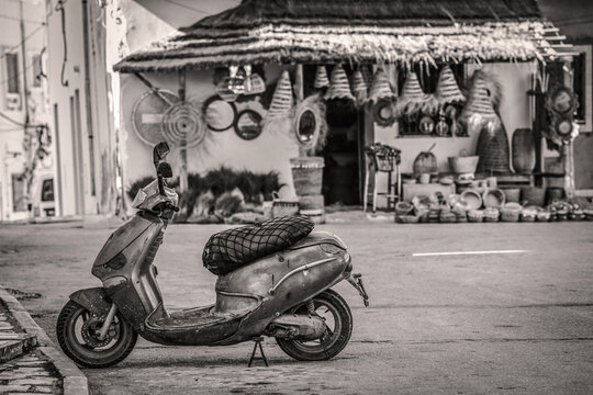 Scooter gar&eacute; devant un magasin d'articles en rotin