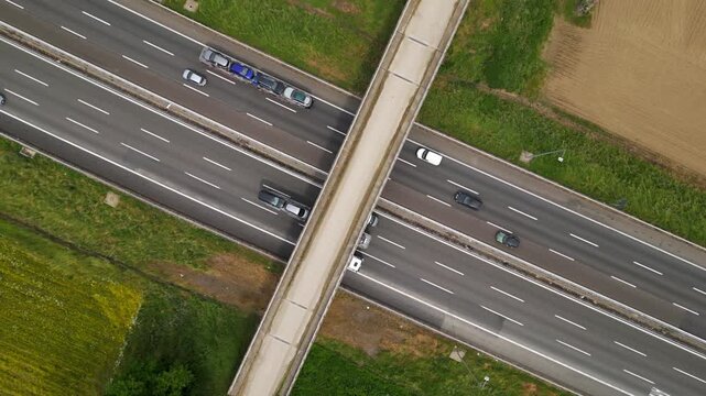 Aerial Highway Intersection: An overhead shot showcases the dynamic intersection of a busy highway, highlighting the flow of traffic beneath a pedestrian bridge amidst the surrounding landscape.
