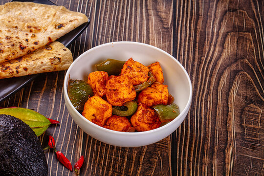 Indian Paneer Tikka Masala inl with Roti bread on a dark wooden table