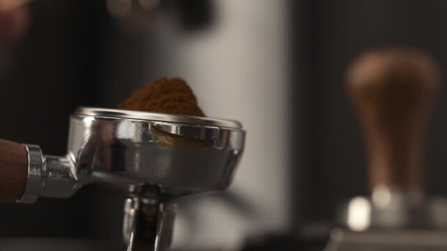 Slow motion man spreading freshly ground coffee in portafilter