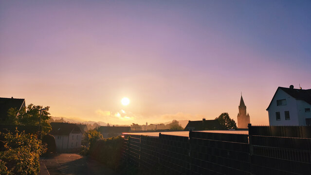 Serene sunrise over a quiet European village with a prominent church spire
