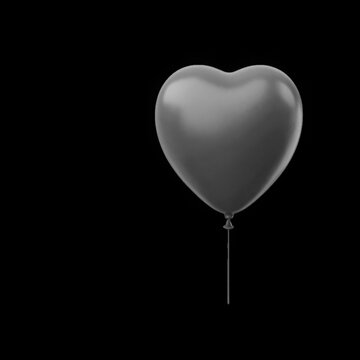 Heart-shaped balloon floating against black background in studio lighting