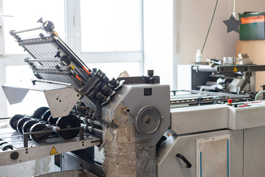 Close-up of industrial printing press finishing machine in print shop. Printing, production and industrial equipment, manufacturing environment.