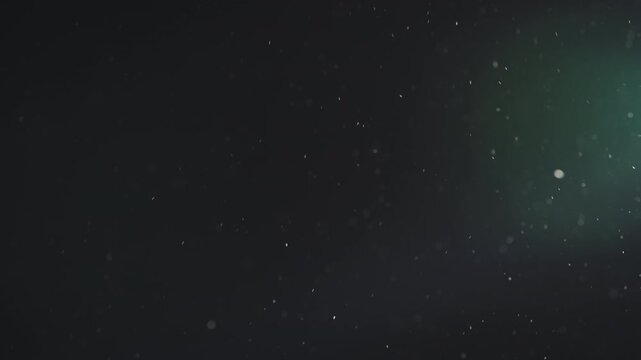 Slow motion real dust particles floating mid air over dark background
