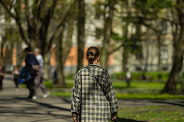 Obraz premium Unrecognizable person walking through sunny urban park with soft focus background and spring atmosphere