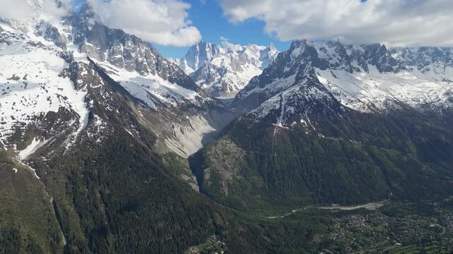 Epic aerial drone view of the Mer de Glace glacier flowing through the rugged alpine mountains near Chamonix, France, with towering snowy peaks and dramatic landscapes of the Mont Blanc massif capture