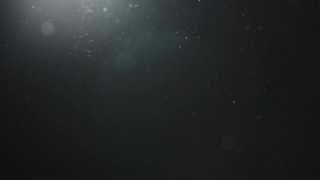 Slow motion real dust particles floating mid air over dark background