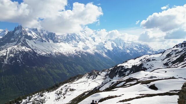 Young couple standing on a mountain summit overlooking the Mer de Glace valley in Chamonix, France, filmed in cinematic slow motion