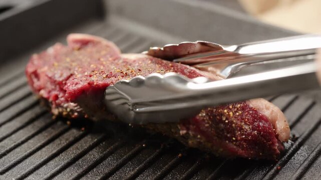 Slow motion flip new york steak with tongs on grill pan