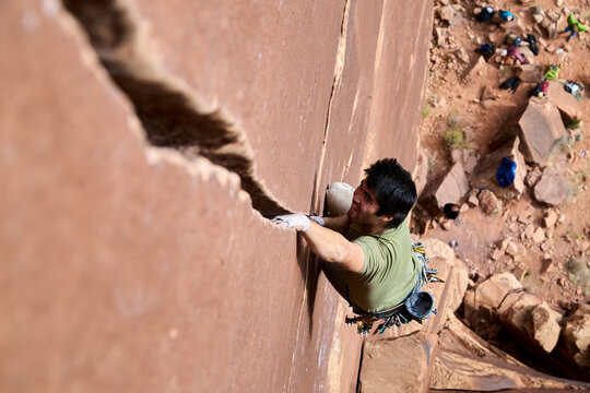 Rock climber crack climbing sandstone wall with determination