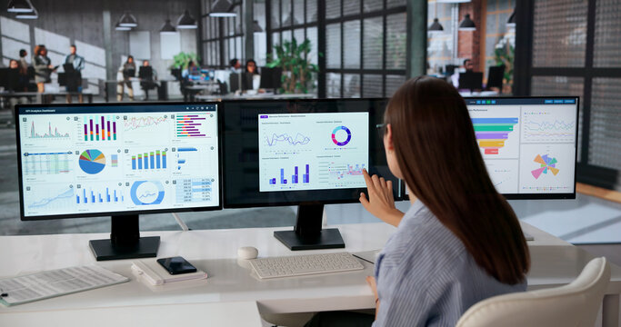 Young Female Data Analyst Studying Multiple Financial Dashboards