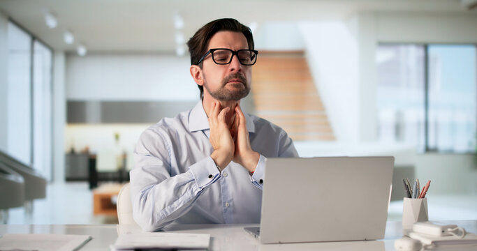 Man Touching Sore Throat While Using Laptop
