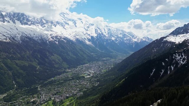 Epic aerial drone view of the Mer de Glace glacier flowing through the rugged alpine mountains near Chamonix, France, with towering snowy peaks and dramatic landscapes of the Mont Blanc massif capture