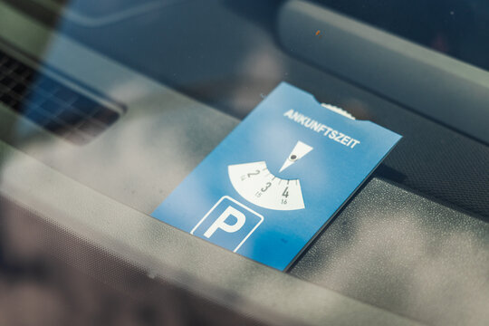 German parking disc with inscription "Ankunftszeit" meaning "arrival time" placed inside car windshield for time limited parking regulation