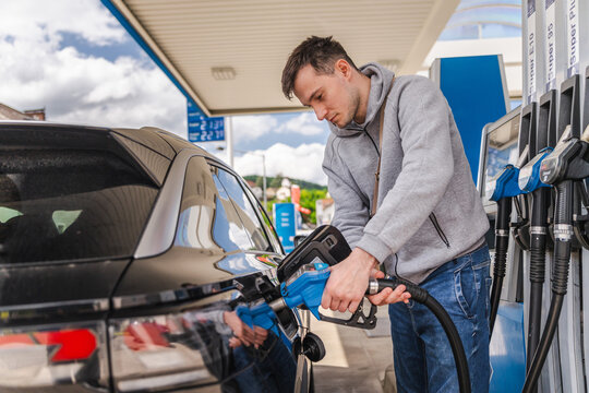Young man refueling black car at modern gas station with gasoline pump during everyday transportation and travel