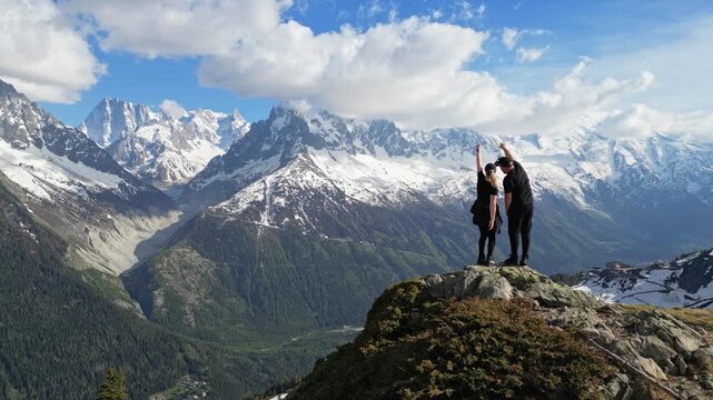 Romantic couple celebrating on an alpine summit above the Mer de Glace valley in Chamonix, France, with snowy mountains in the background, captured in cinematic slow motion