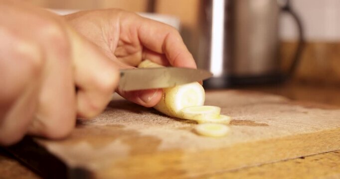 Chef hands slicing white root vegetable on cutting board