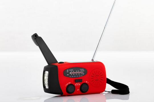 Portable emergency crank radio with flashlight and antenna isolated on light background. Studio product photography for survival, disaster preparedness and emergency concepts.