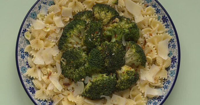 Top view of a plate with farfalle rigate pasta with steamed broccoli.