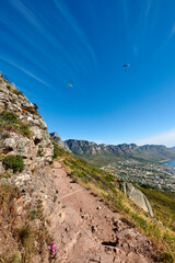 Naklejka premium Mountain, hiking trail and travel outdoor, paragliding or blue sky with path to explore. Terrain, hill and trekking environment for adventure, sightseeing and destination with space on cliff