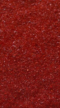 Korean red chili pepper flakes (gochugaru) as a background texture. An important ingredient in kimchi and gochujang paste. Selective focus, vertical video.