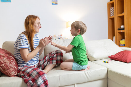 Mother and child play clapping game at home during daytime in cozy living room setting