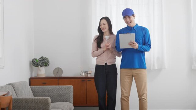 若い女性の引っ越しの見積もりをする若い業者　ライフスタイルイメージ