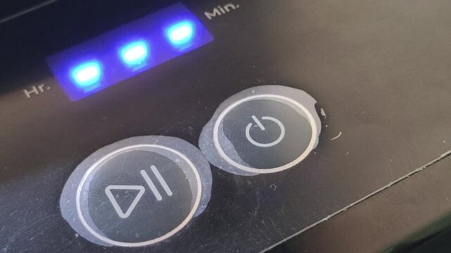 Extreme closeup of finger pushing round plastic power button or switch on the electrical appliance to start the machine. Concept of using electric equipment for daily household work.