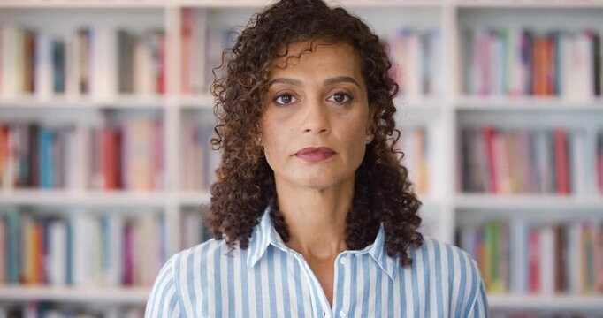 Face, serious and woman in library for education, university professor or confidence for teaching. Portrait, literature or mature educator with research for English course, knowledge sharing or space