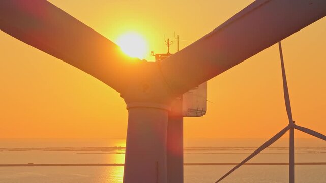 Offshore wind turbine blades rotating at sunset