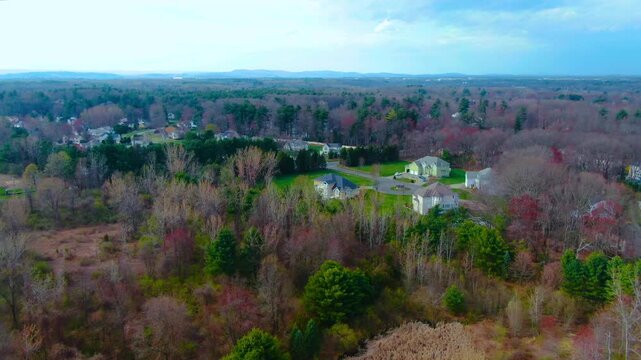 Drone shot moving backward over a suburban neighborhood with trees during a spring afternoon in Windsor Connecticut