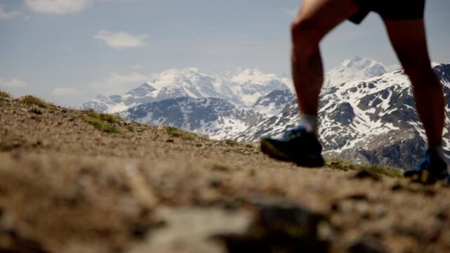 Runner's Legs Walking Up Rocky Alpine Trail During The Livigno SkyMarathon In Italy. ground-level shot, slow motion