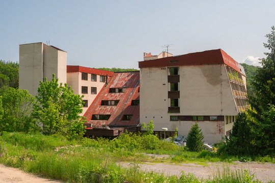 View of the abandoned hotel Junior in Krpacovo with its decaying brutalist architecture and rusty red roof surrounded by lush green forest in Dolna Lehota, Banskobystricky kraj, Slovakia.