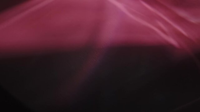 Abstract video of rippling red caustic light reflections and patterns dancing fluidly over a dark, moody background.
