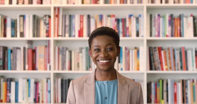 Education, face and woman teacher in school library for development, knowledge or syllabus. Books, learning and smile with black person on campus for college or university course and curriculum