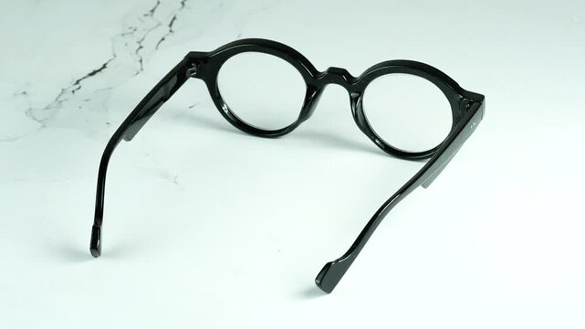 Modern Round Black Plastic Glasses With Dioptre That Rotate 360 ​​Degrees on a White Background, Stylish Optical Frames, 4K Video