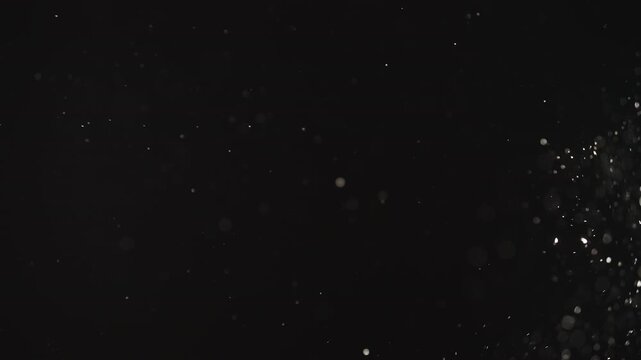 Slow motion real dust particles floating mid air over dark background